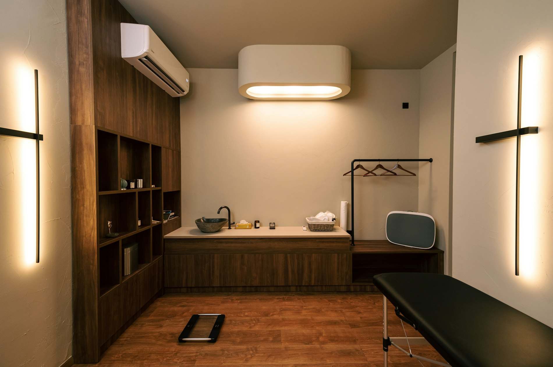 Sala de atendimento com maca, armários de madeira e janela